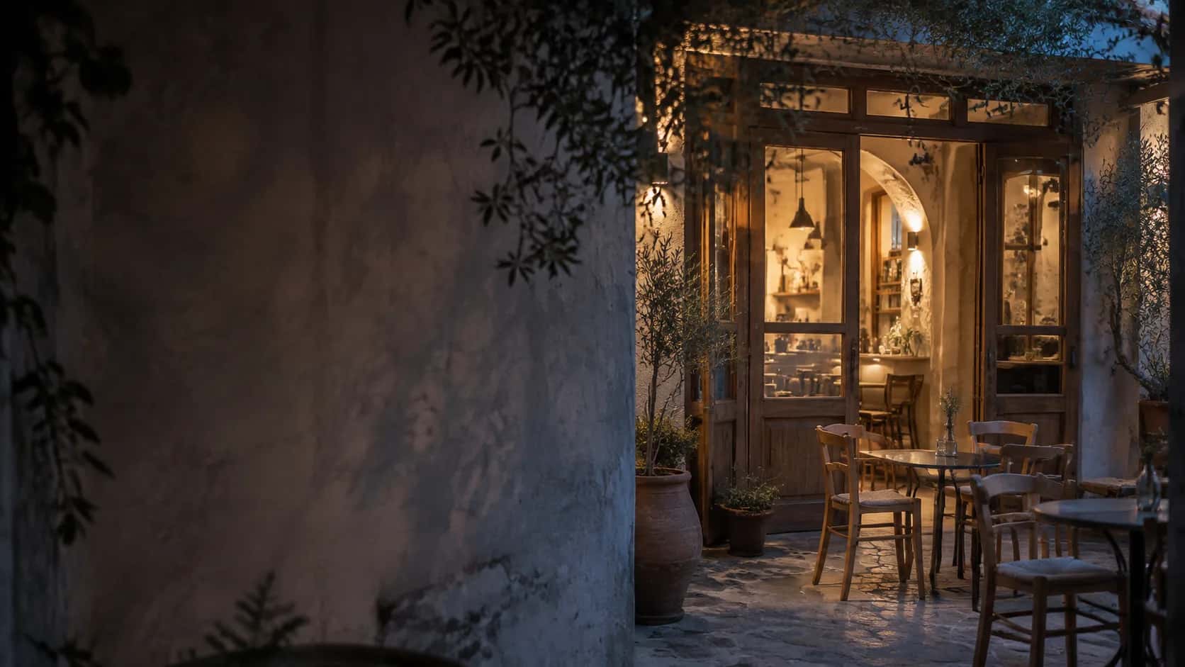 Warm beleuchteter Caféhof mit Tischen und Stühlen in der Abenddämmerung.